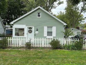 A mint green house with a white fence.
