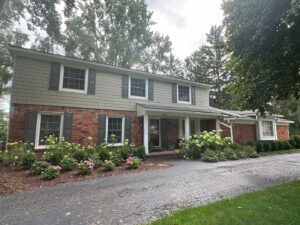 A landscape picture of a brick house with a freshly landscaped garden.